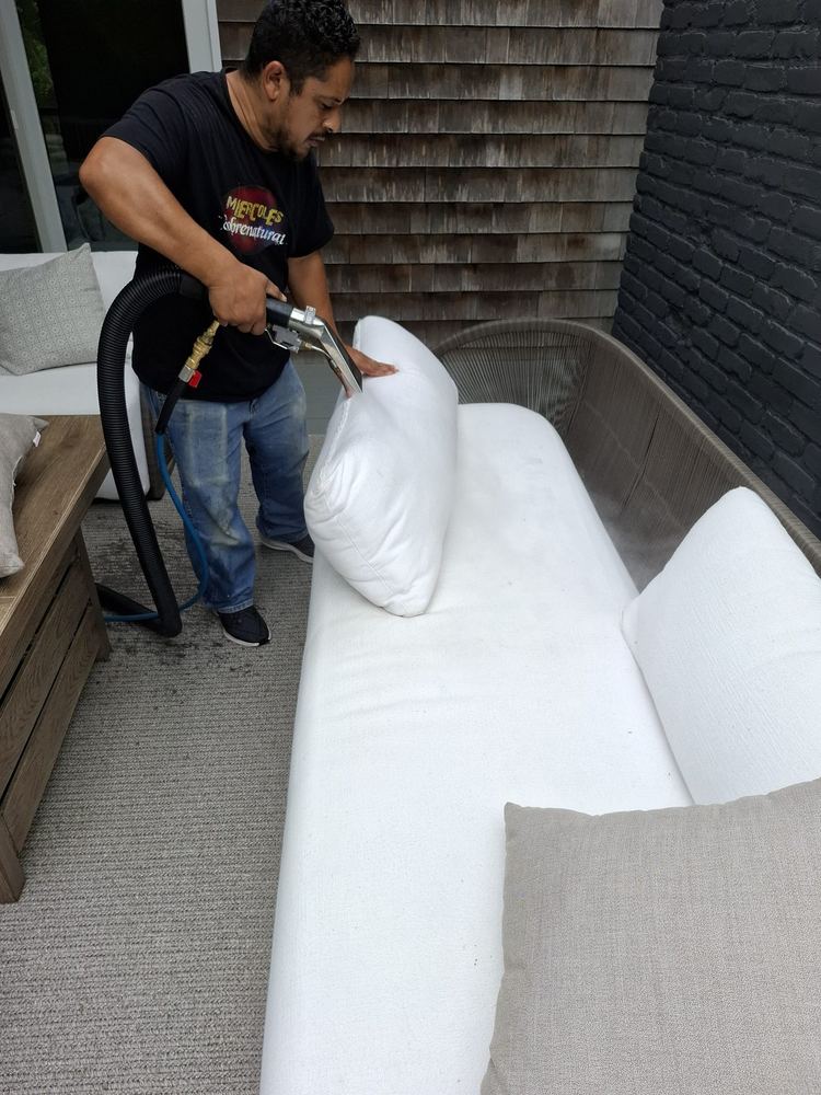 Green Choice technician steam cleaning a white sectional cushion on Long Island